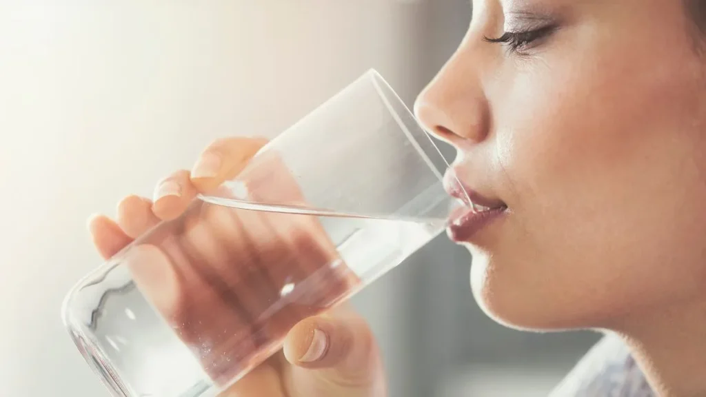 magnesio e potassio disciolti in un bicchiere d'acqua che viene bevuto da una donna